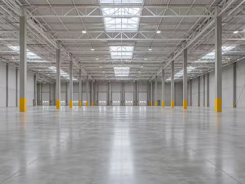 Interior de nave vacía con estructura de acero y piso de concreto pulido